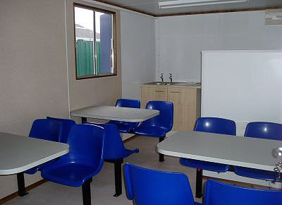 inside container showing tables and seating with small basin area