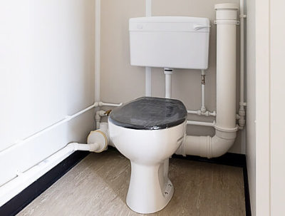 White toilet with black seat inside a portable toilet container